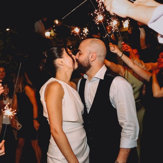 A couple kissing under a sparkler arch